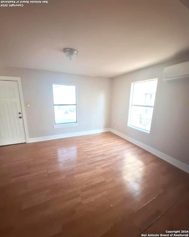 spare room featuring wood-type flooring and an AC wall unit