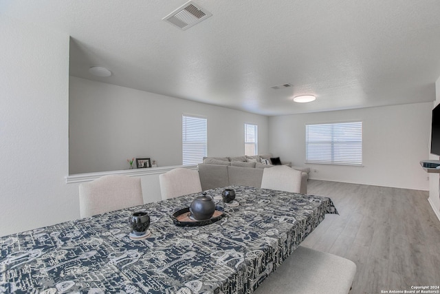 dining space featuring a textured ceiling and light hardwood / wood-style floors