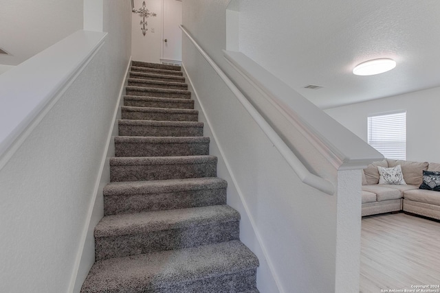 staircase with hardwood / wood-style floors and a textured ceiling