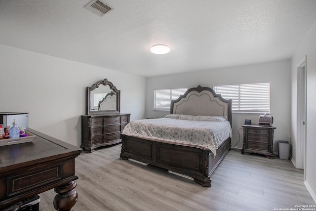 bedroom with a textured ceiling and light wood-type flooring