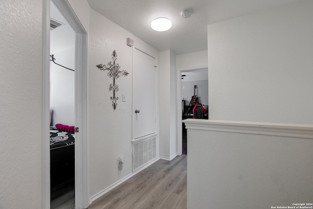 hall featuring light hardwood / wood-style flooring and a textured ceiling