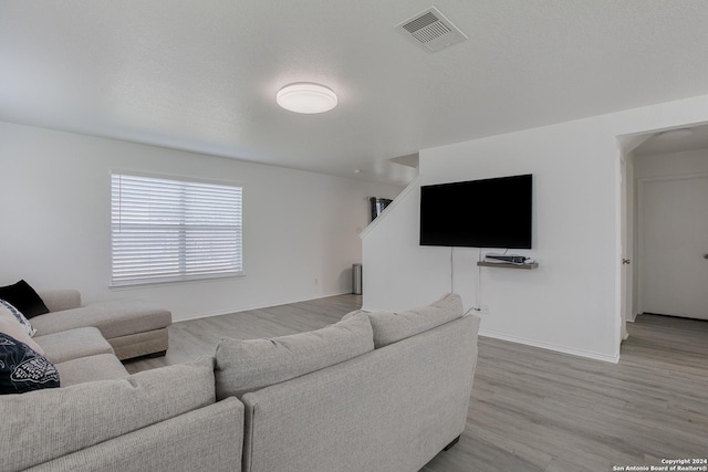 living room with light wood-type flooring and a textured ceiling