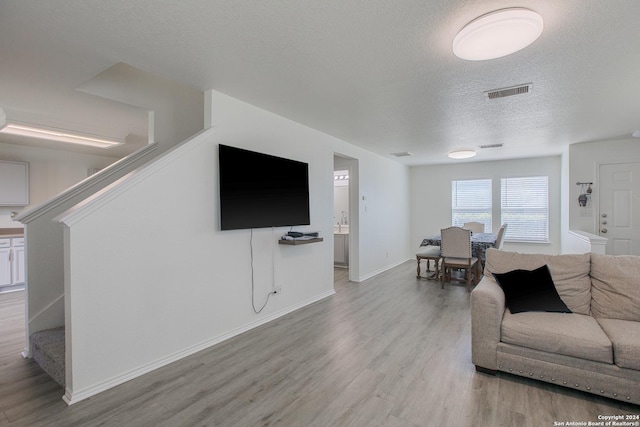 living room with light hardwood / wood-style floors and a textured ceiling