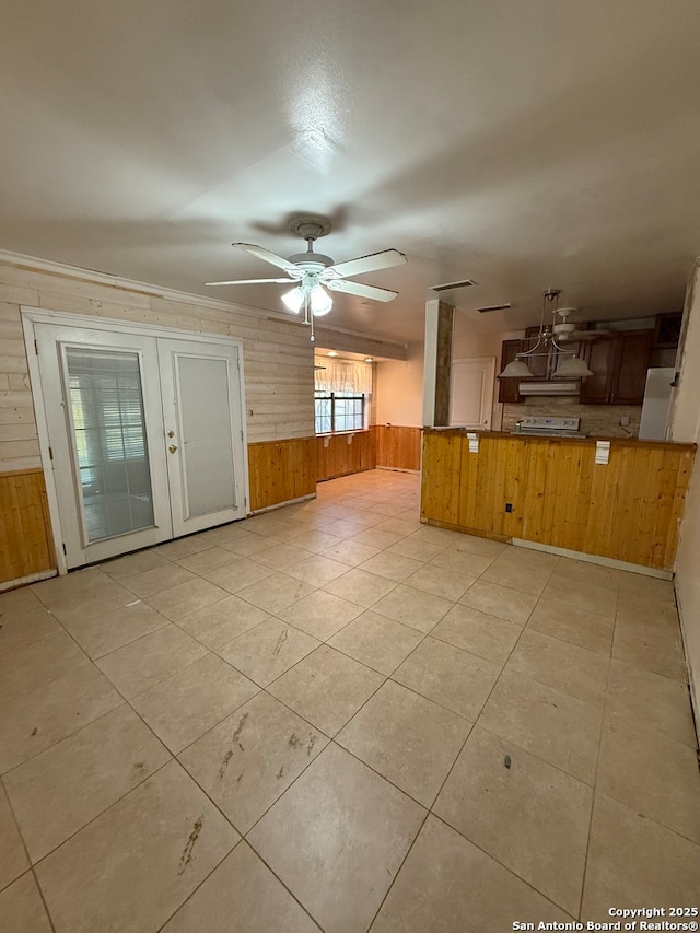 unfurnished living room featuring wooden walls and ceiling fan