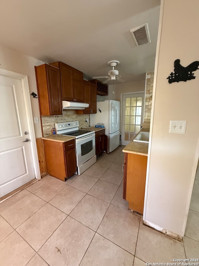 kitchen with ceiling fan, light tile patterned flooring, white appliances, and backsplash