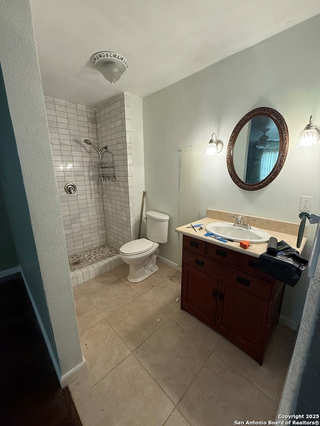 bathroom with a tile shower, vanity, toilet, and tile patterned floors