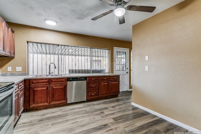 kitchen with a textured ceiling, sink, appliances with stainless steel finishes, and light hardwood / wood-style flooring