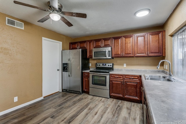 kitchen with ceiling fan, sink, stainless steel appliances, and light hardwood / wood-style flooring