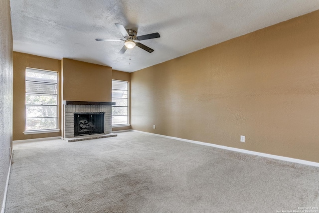 unfurnished living room with ceiling fan, a fireplace, carpet floors, and a textured ceiling