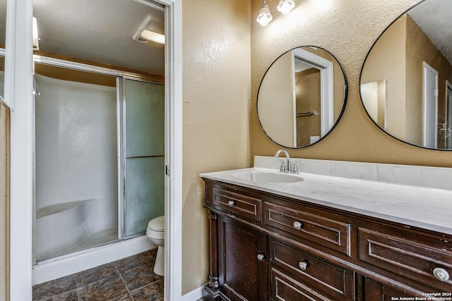 bathroom featuring vanity, toilet, and a shower with door