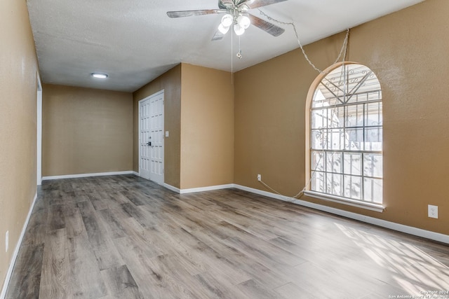 empty room with ceiling fan, a textured ceiling, and hardwood / wood-style flooring