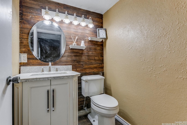 bathroom featuring vanity, toilet, and wooden walls