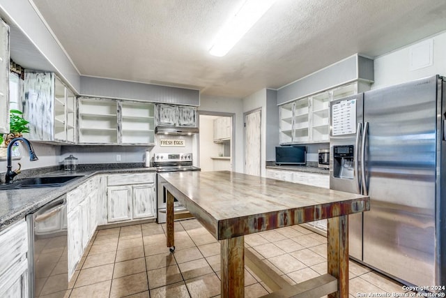 kitchen featuring appliances with stainless steel finishes, a textured ceiling, light tile patterned floors, and sink