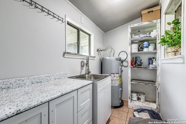 washroom with water heater, sink, and light tile patterned floors