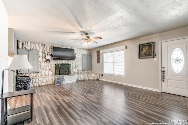 unfurnished living room with ceiling fan, dark hardwood / wood-style flooring, and a fireplace