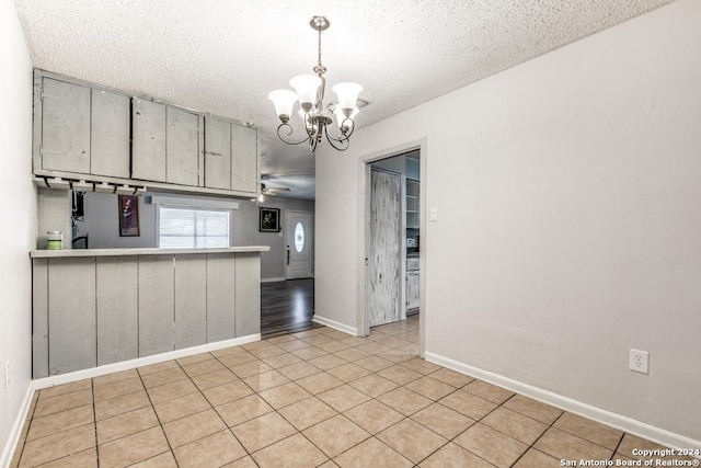 kitchen featuring kitchen peninsula, a textured ceiling, ceiling fan with notable chandelier, light tile patterned floors, and decorative light fixtures