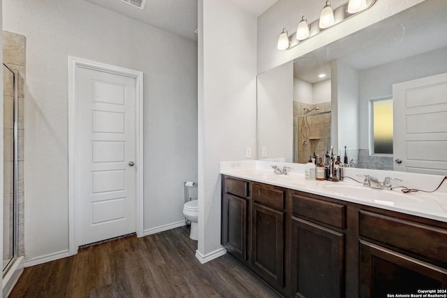 bathroom featuring wood-type flooring, vanity, toilet, and walk in shower