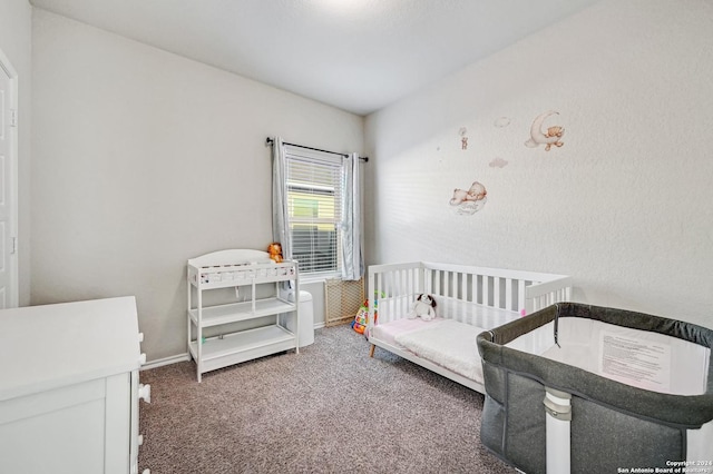 bedroom with dark carpet and a nursery area