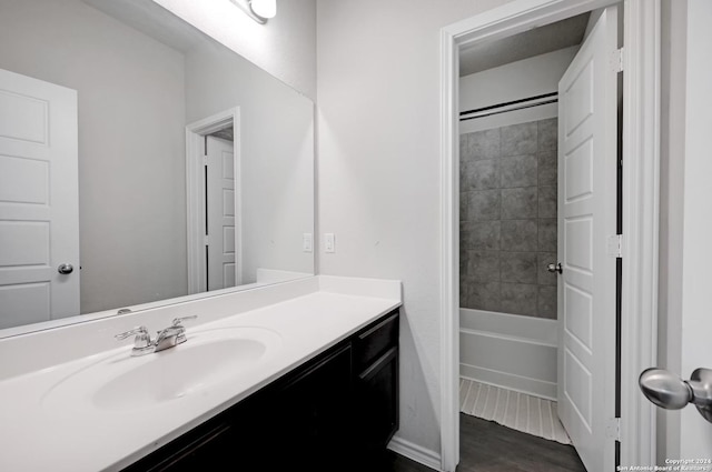 bathroom featuring wood-type flooring, vanity, and tiled shower / bath