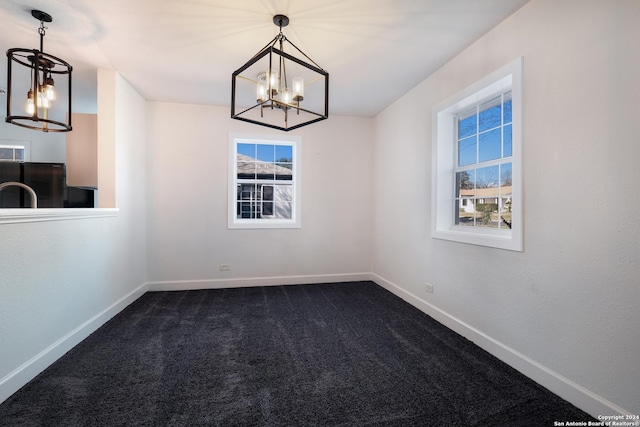 spare room with carpet and an inviting chandelier