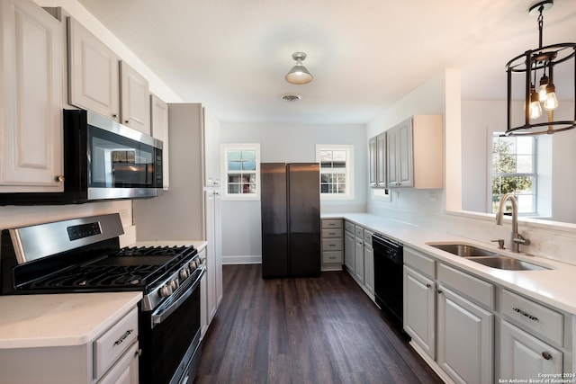 kitchen featuring dark hardwood / wood-style flooring, stainless steel appliances, sink, white cabinets, and hanging light fixtures