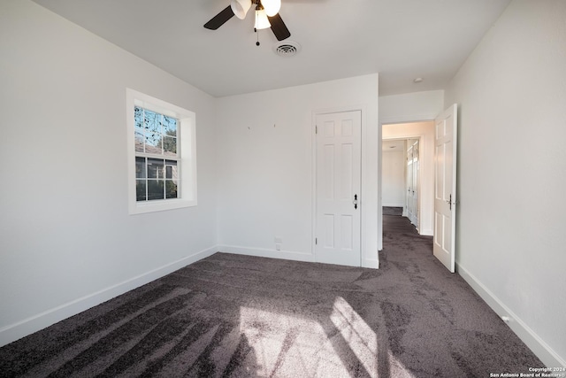 unfurnished bedroom with ceiling fan and dark carpet