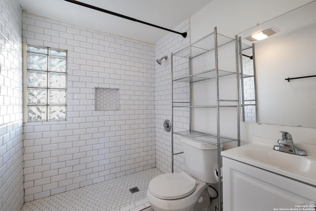 bathroom with a tile shower, vanity, and toilet