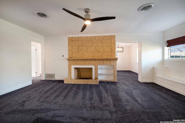 unfurnished living room featuring ceiling fan, dark carpet, and a fireplace