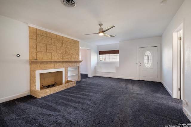 unfurnished living room with dark colored carpet, a large fireplace, and ceiling fan