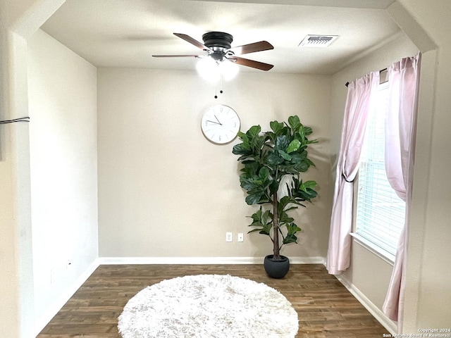 living area featuring ceiling fan and dark wood-type flooring