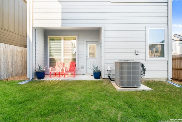 rear view of house featuring a lawn, cooling unit, and a patio