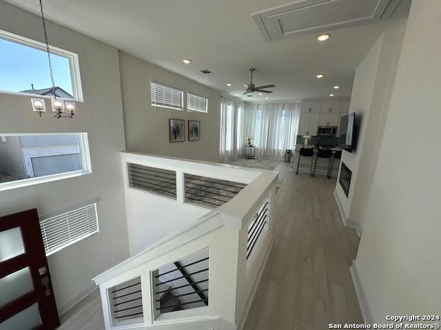 kitchen with white cabinets, ceiling fan with notable chandelier, light hardwood / wood-style flooring, and hanging light fixtures