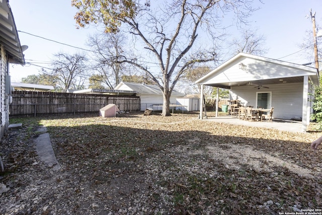 view of yard featuring ceiling fan, a storage shed, and a patio