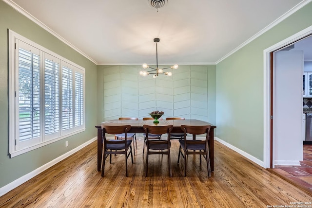 dining area with a chandelier, wood-type flooring, and crown molding