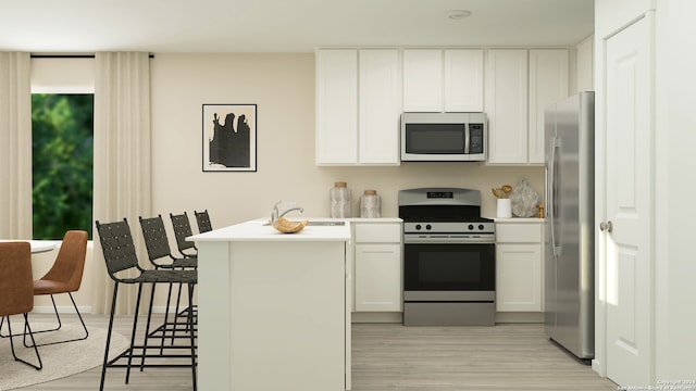 kitchen with a breakfast bar, sink, light hardwood / wood-style flooring, appliances with stainless steel finishes, and white cabinetry