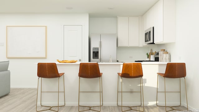 kitchen with white refrigerator with ice dispenser, light wood-type flooring, a kitchen bar, white cabinets, and range