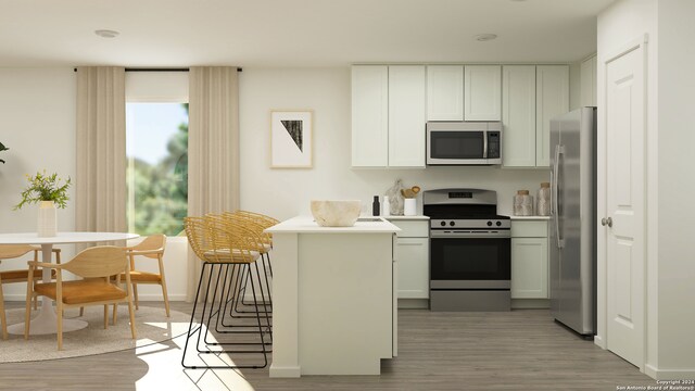 kitchen with white cabinets, appliances with stainless steel finishes, kitchen peninsula, and wood-type flooring