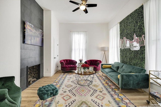 living room featuring hardwood / wood-style flooring, ceiling fan, and a tile fireplace