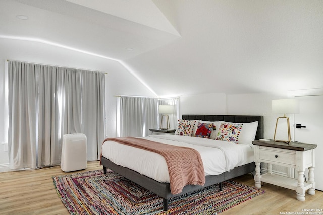 bedroom with light wood-type flooring and lofted ceiling