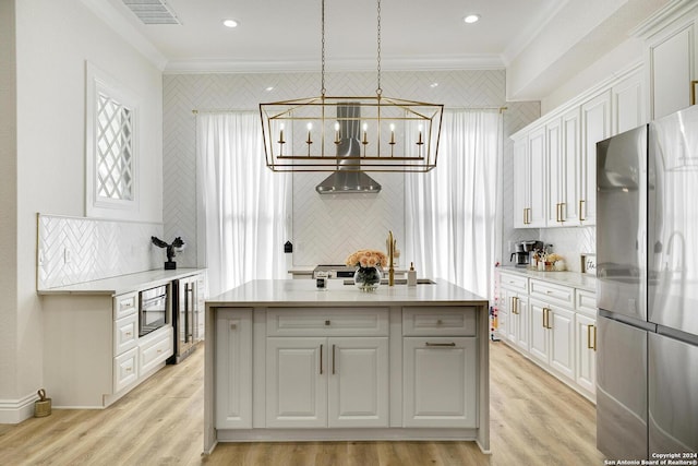 kitchen with pendant lighting, stainless steel fridge, crown molding, and a kitchen island with sink