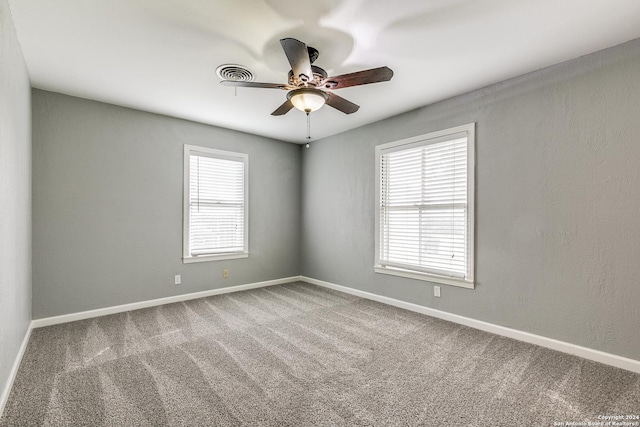 carpeted spare room with a wealth of natural light and ceiling fan