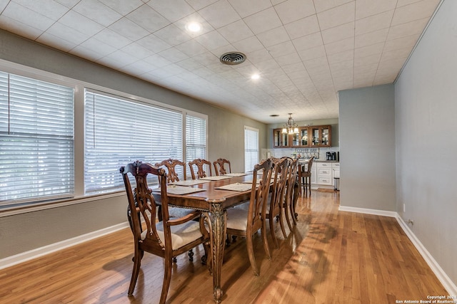 dining space with light hardwood / wood-style flooring, a wealth of natural light, and a notable chandelier