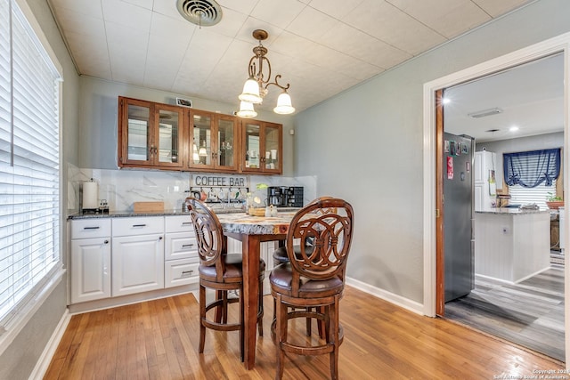 dining space featuring plenty of natural light, light wood-type flooring, and a chandelier