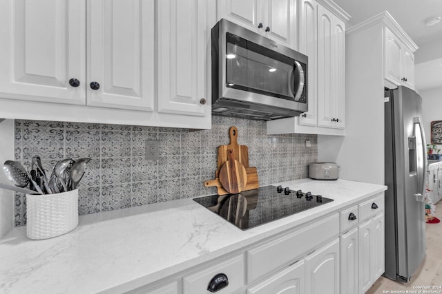 kitchen with appliances with stainless steel finishes, backsplash, white cabinetry, and light stone counters