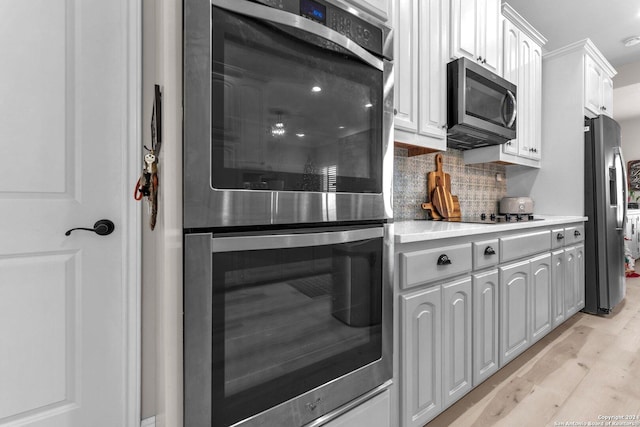 kitchen with tasteful backsplash, light hardwood / wood-style flooring, white cabinets, and stainless steel appliances