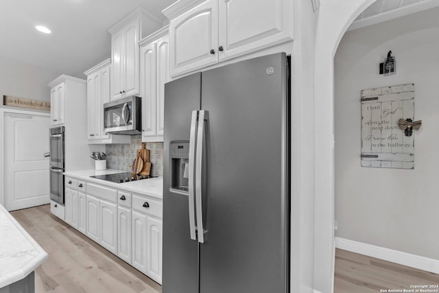 kitchen featuring tasteful backsplash, white cabinetry, light hardwood / wood-style flooring, and appliances with stainless steel finishes