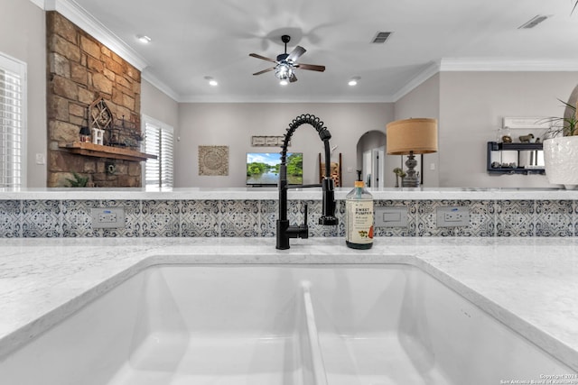 details with light stone countertops, sink, ceiling fan, decorative backsplash, and ornamental molding