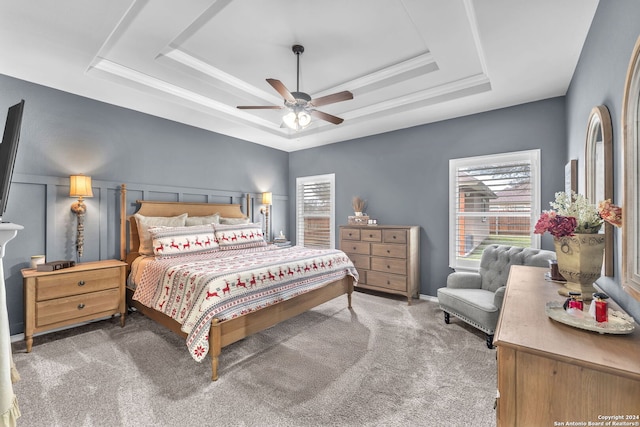 carpeted bedroom featuring a raised ceiling and ceiling fan