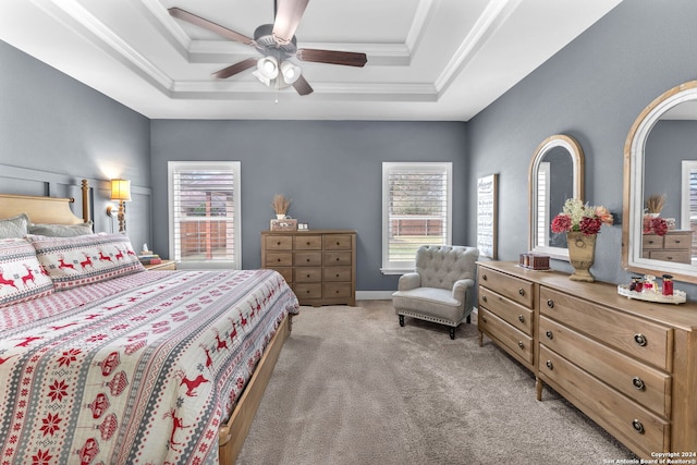 bedroom with a raised ceiling, ceiling fan, light colored carpet, and multiple windows