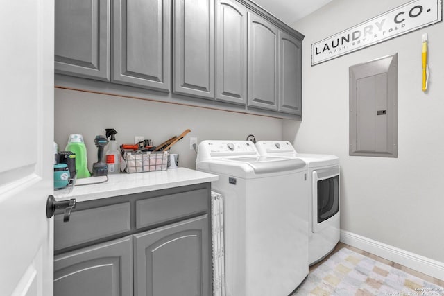 laundry room featuring washing machine and clothes dryer, electric panel, and cabinets